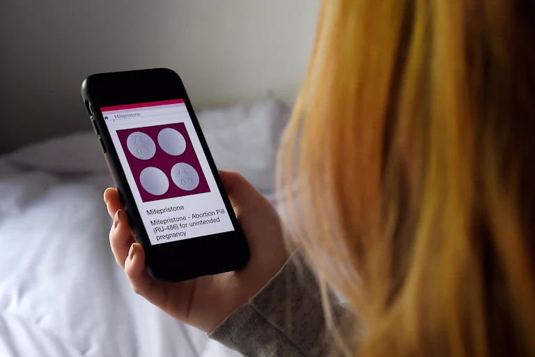 A woman looks at Mifepristone, an abortion pill for unintended pregnancy, on her phone screen.