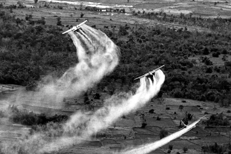 Airplanes release some gas over a forest landscape.