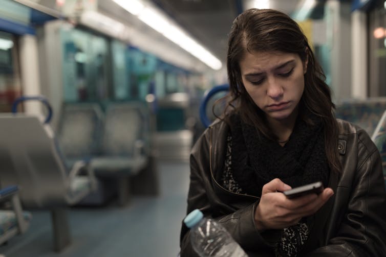 Young woman looking worried on a phone.