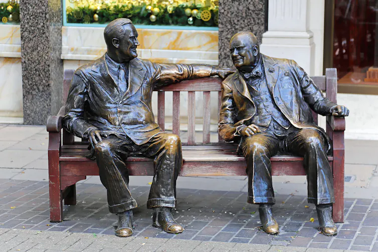 bronze sculptures of Franklin D Roosevelt and Winston Churchill on a wooden bench.