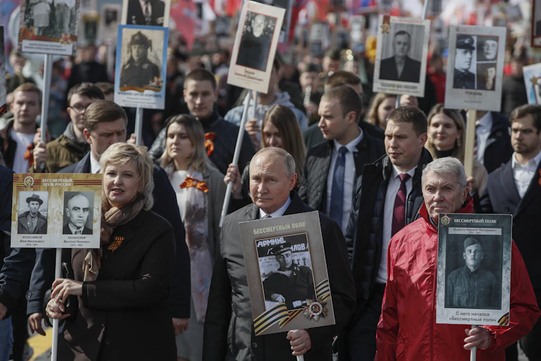Russian president, Vladimir Putin, and Russian people carry portraits of their relatives, participants of World War II during an Immortal Regiment memorial demonstration in Moscow.
