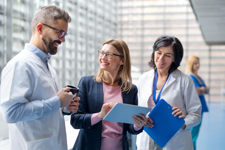 A man and a woman in white coats talking to a woman in business clothes