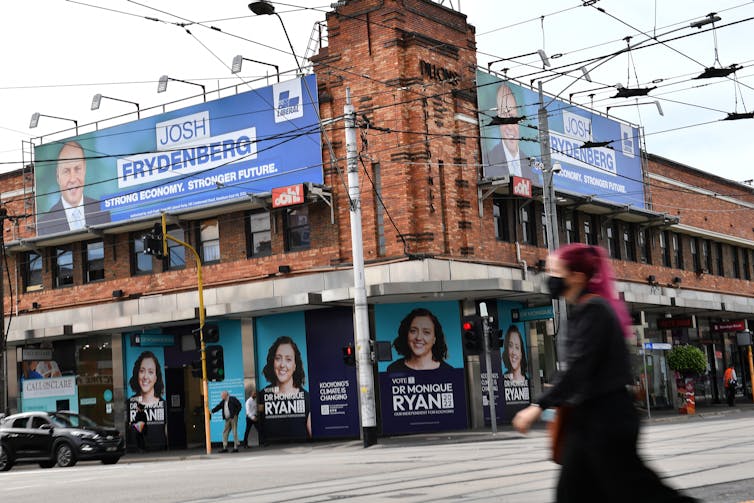 woman walks past building with election signs