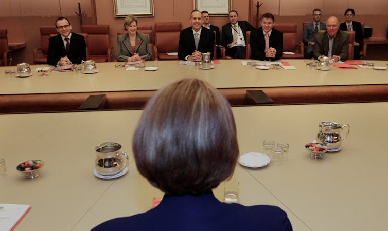 back of woman's head and a group of people in suits at a table
