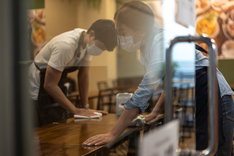 Workers clean tables in a restaurant.