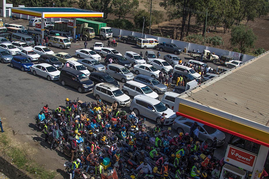 Motorists and motorcycle riders queue outside a filling station