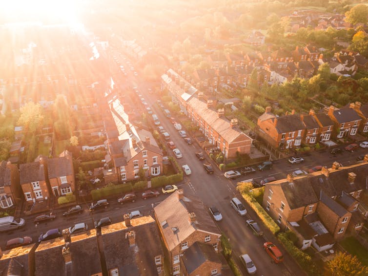 Sun setting with lens flare and warm colours, over a traditional British neighbourhood.