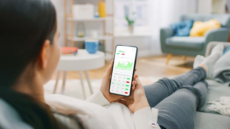 Woman holding phone showing investment details.