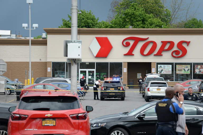 Police tape drapes across a car park in front of a Tops Friendly supermarket.