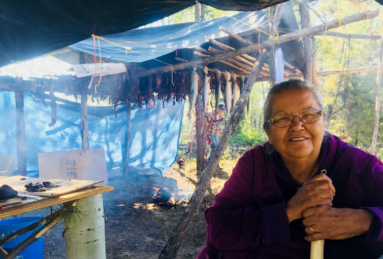 an elder sitting in front of fish surrounded by smoke