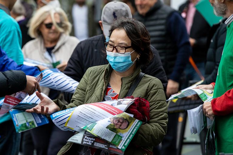 A woman voter is inundated with how-to-vote cards during the 2022 election.