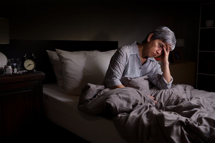 Elderly woman sitting up in bed, unable to sleep during the night.