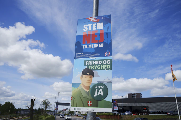 A roadside pole with two opposing campaign signs telling people to vote against or for the EU defence referendum