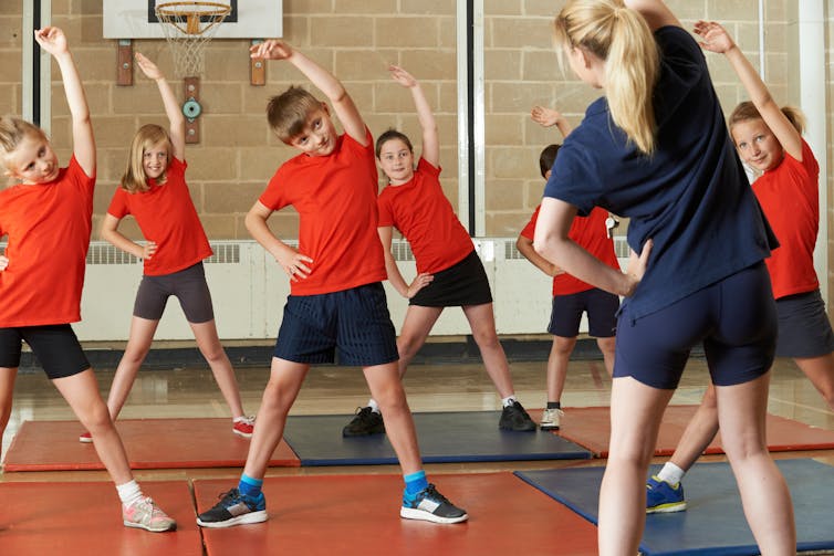 Teacher leading a group of students in stretches