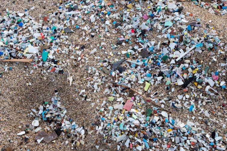 A swath of small colored plastic bits on a beach.