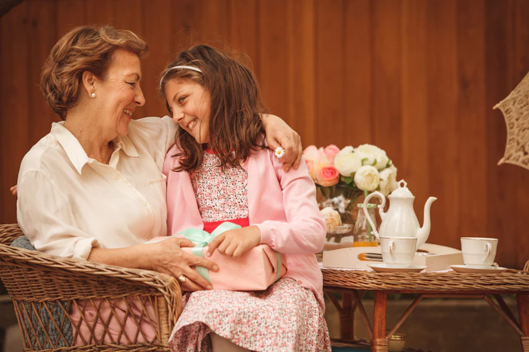 woman holds girl on her lap with tea set on table