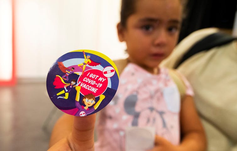 a young girl shows her sticker 