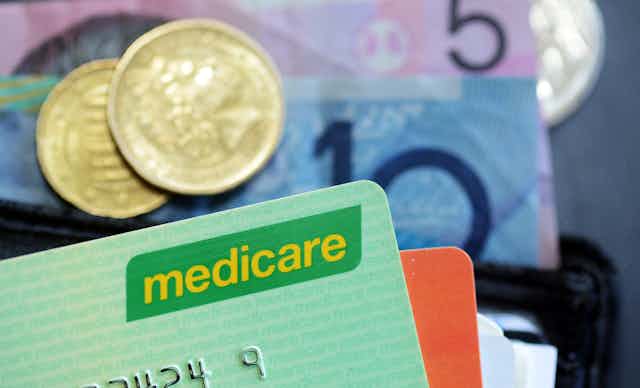 Medicare card and money coming out of a wallet.
