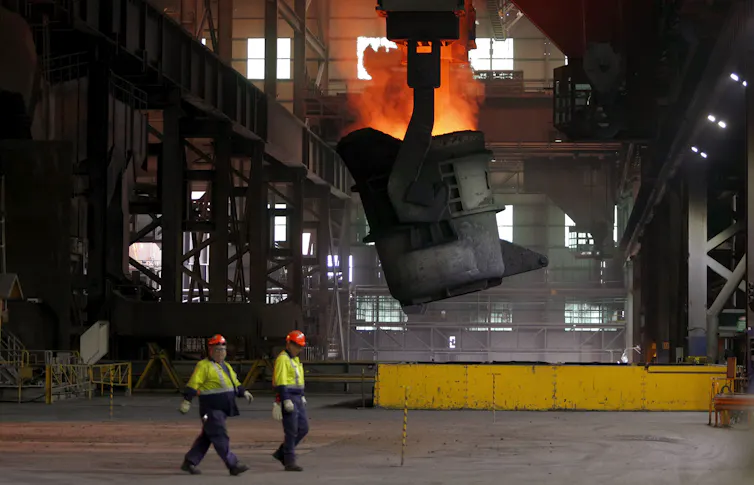 two workers walk past furnace