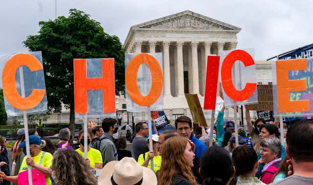 Demonstrators holding up letters spelling CHOICE with the U.S. Supreme Court building in the background