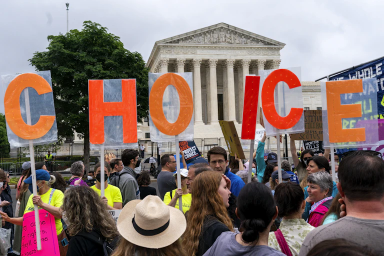 Demonstrators holding up letters spelling CHOICE with the U.S. Supreme Court building in the background