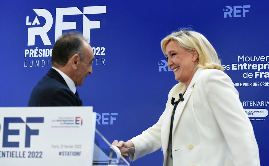 Eric Zemmour et  Marine Le Pen, se serrent la main en se croisant lors de la présentation de leurs programmes de campagne économique au Medef à Paris, le 21 février 2022.