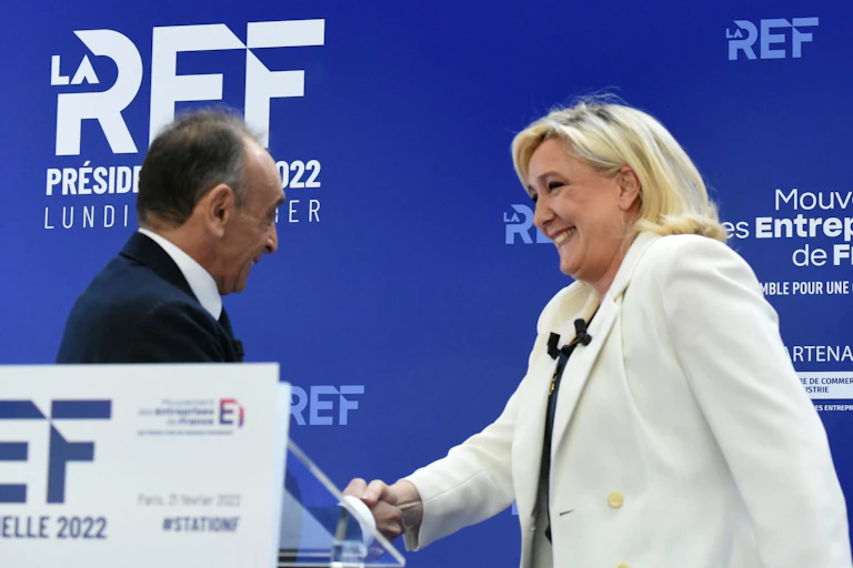 Eric Zemmour et Marine Le Pen, se serrent la main en se croisant lors de la présentation de leurs programmes de campagne économique au Medef à Paris, le 21 février 2022.