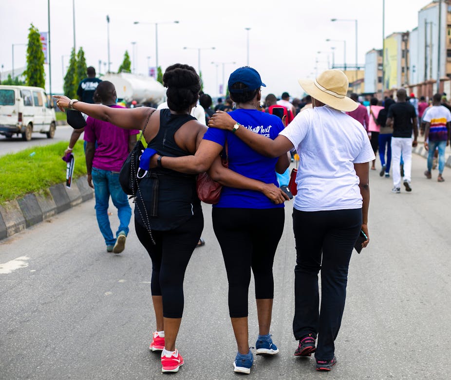 The back view of a group of women who are wearing fitness attire and participating in a walk. 