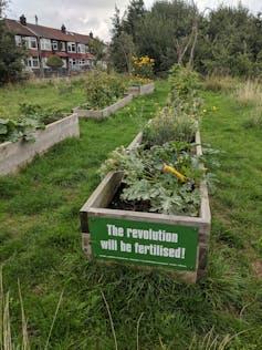 Plants in a planter, with a sign reading 'The revolution will be fertilised!'