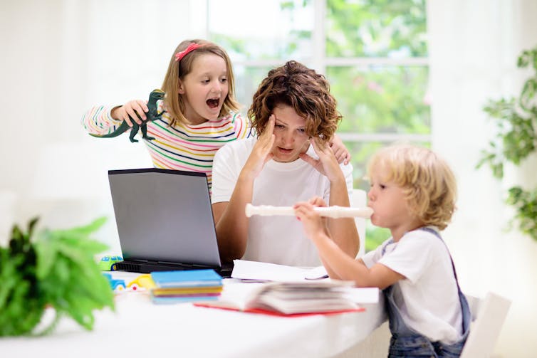Stressed mother trying to work with two children making noise
