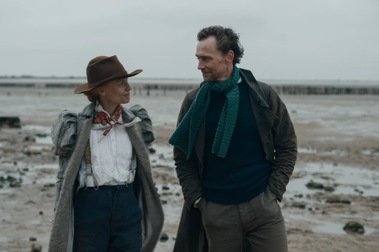 Man and woman walk along a beach.