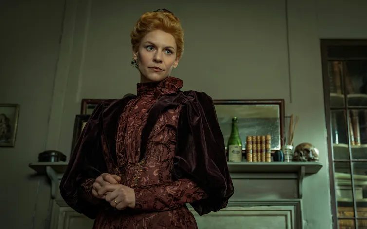 A woman in period dress in a living room.