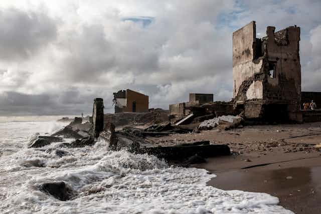 Sea beats against destroyed buildings on a beach