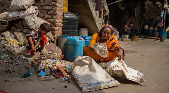 A woman in a sari sorts through trash, a small boy beside her