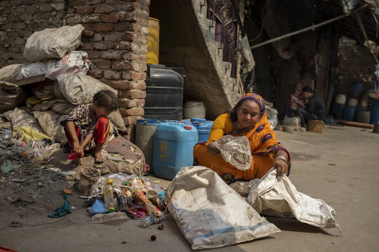 A woman in a sari sorts through trash, a small boy beside her