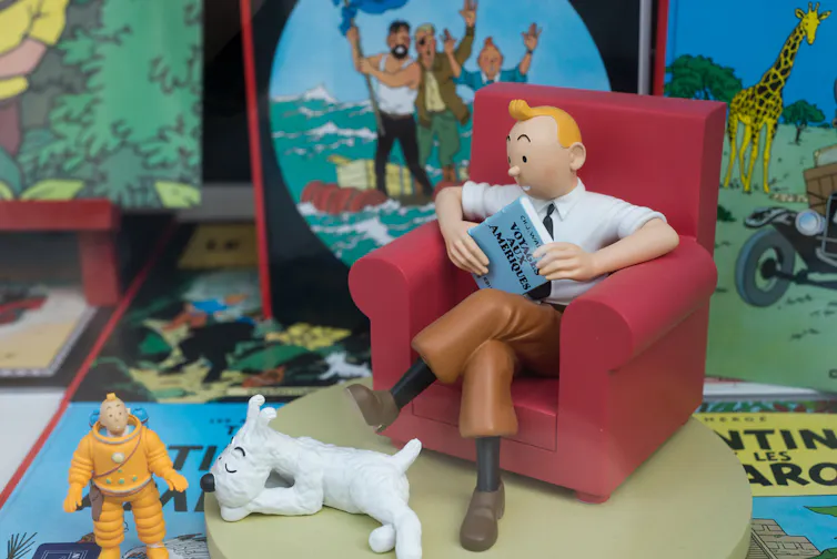 tintin sur un fauteuil avec Milou à ses pieds