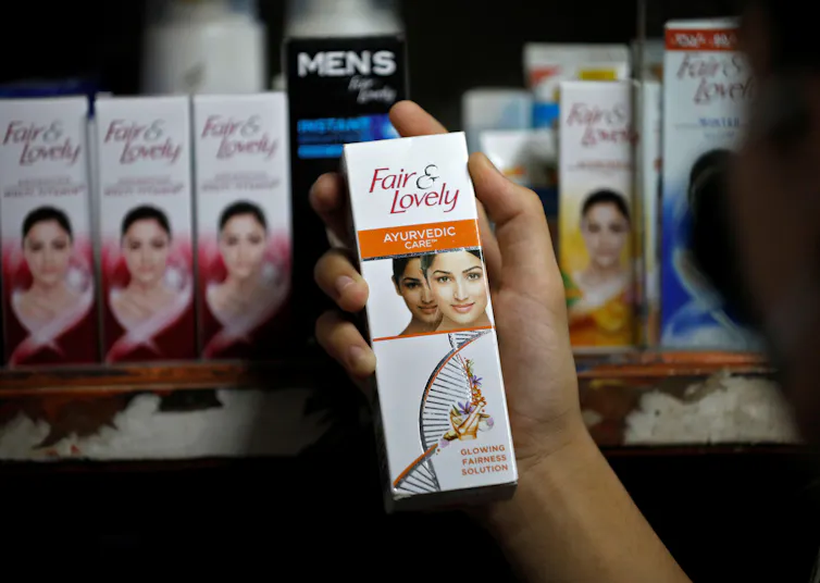 A customer holds up a box of Fair & Lovely skin lightener in a shop.