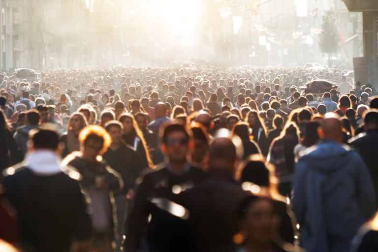 Une foule très dense avance dans une rue brumeuse