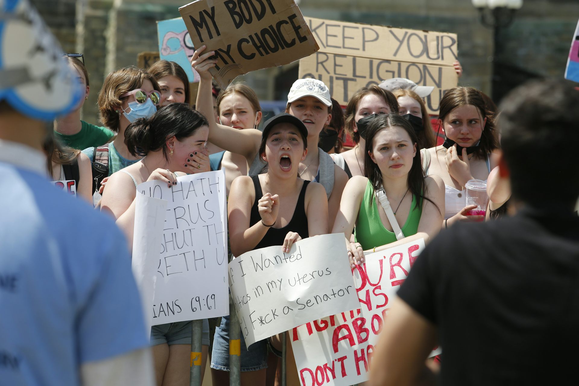 A woman holds up a sign that reads 'if I wanted politics in my uterus I would f*ck a senator.'