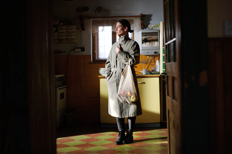 A woman stands alone in a simple kitchen.