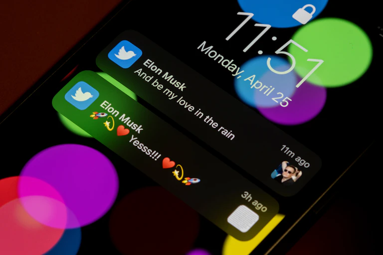 Two of Elon Musk's tweets are visible on the lock screen of a smartphone