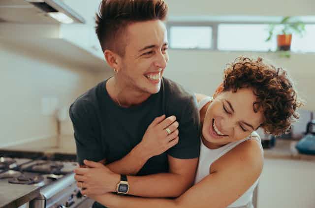 Two people laughing and cuddling in kitchen