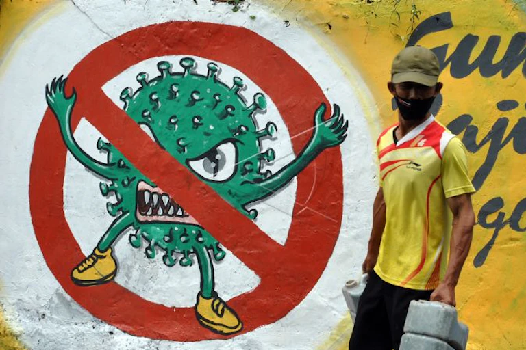 Warga menggunakan masker berjalan di samping mural bergambar COVID-19 di Kota Bogor, Jawa Barat