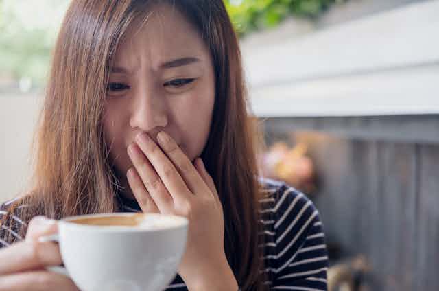 woman looks distressed after sip of coffee