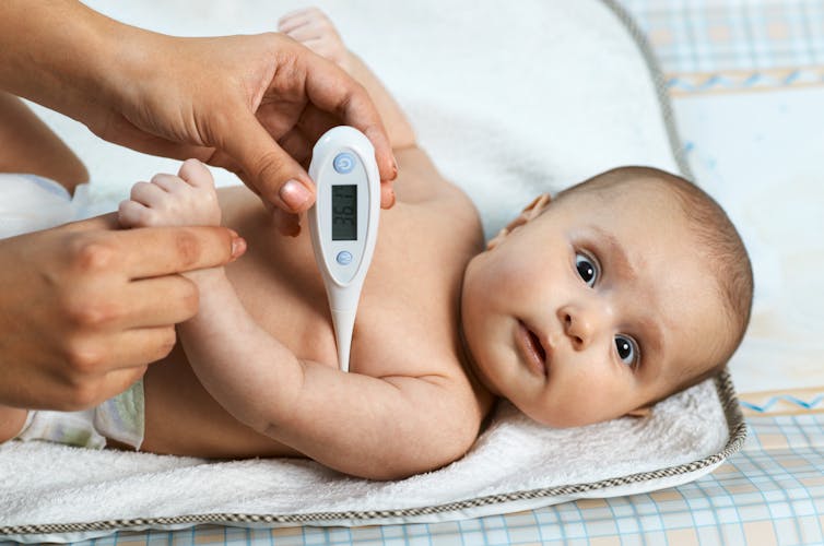 Baby with thermometer under its arm.