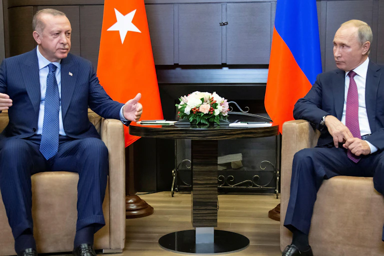 Two men in suits, sitting in brown chairs.