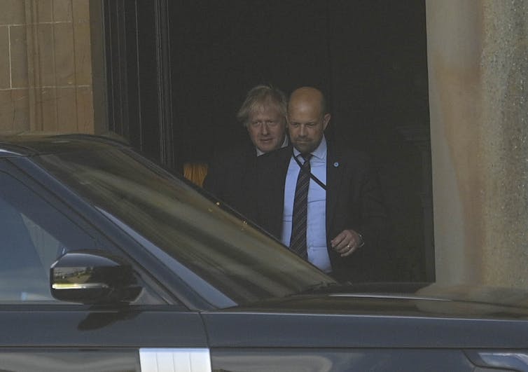 Boris Johnson pictured from afar leaving a building in Northern Ireland and heading towards his car.