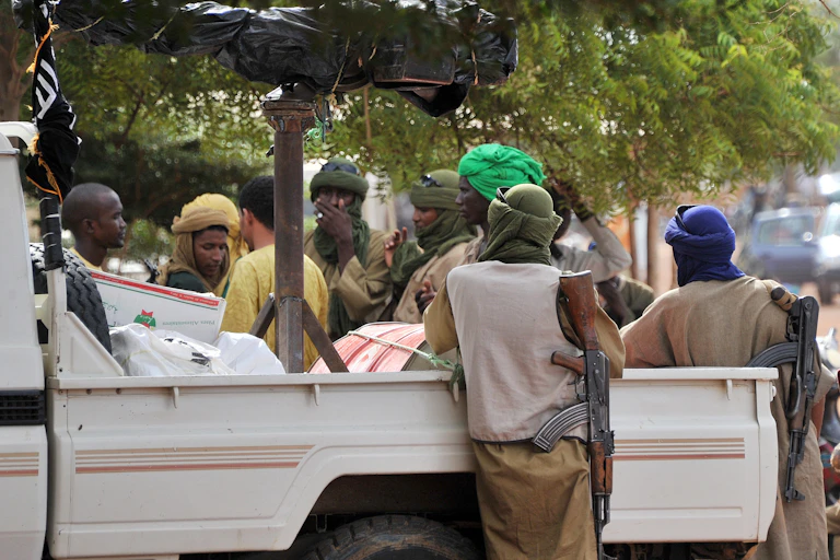 Men holding guns and standing around a pickup truck