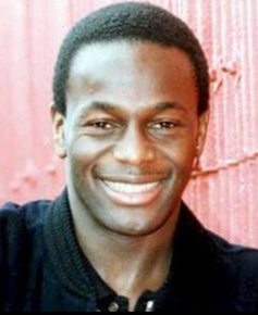 A head shot of UK footballer Justin Fashanu smiling.