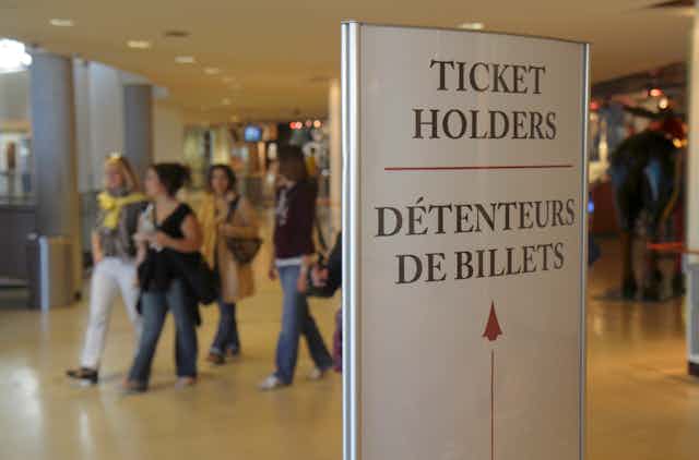 People walk past a sign in both French and English